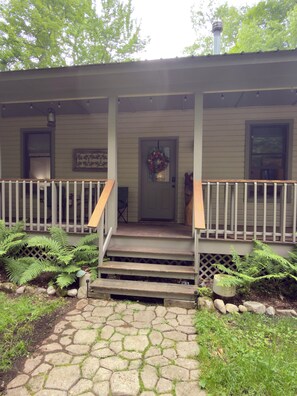 A house with a porch, steps leading to the door, and a stone pathway. - Serene 5-bedroom house in delightful Old Forge perfect for families (Old Forge)