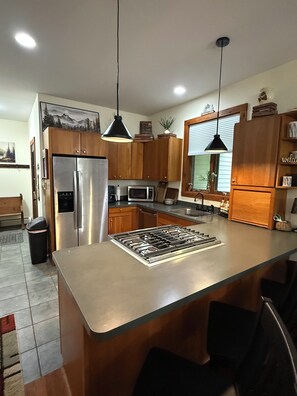 Una cocina moderna con electrodomésticos de acero inoxidable, armarios de madera y una isla central con taburetes de bar.