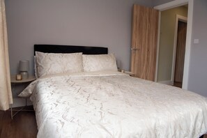 Un dormitorio con cama, mesitas de noche y una puerta.