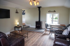 A living room with a fireplace, leather sofa, wooden coffee table, and a TV mounted on the wall. - entire 3 bed home on the outskirts of Donegal Town (Donegal Town)