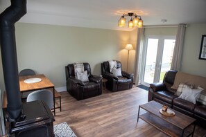 A living room with a dining table, two leather sofas, a coffee table, and a ceiling light fixture. - entire 3 bed home on the outskirts of Donegal Town (Donegal Town)