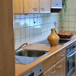 A kitchen with wooden cabinets, a stainless steel sink, and a tiled backsplash. - Vacation Rental with an Extra-Large Natural Garden & Sunny Terrace (Clausthal-Zellerfeld)