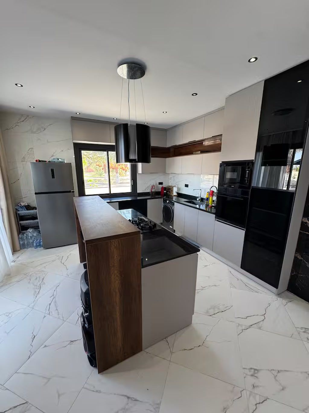 Una cocina moderna con una isla central, electrodomésticos integrados y un amplio ventanal que proporciona luz natural.
