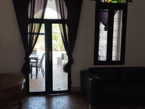 An interior space with a door leading to an outdoor area, a window with decorative iron bars, and a sofa. - STUNNING VILLA - 4 BEDROOMS - PRIVATE POOL - QUIET LOCATION (Unknown)