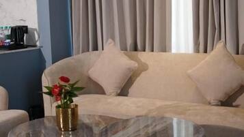 Una sala de estar moderna con un sofá, dos mesas redondas de vidrio y un florero con flores.