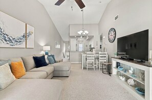A modern living room with a sofa, a dining area, and a kitchen in the background. - Just Listed! Welcome to The Cypress House at La Cita -Golf Course Views and Pool (Titusville)
