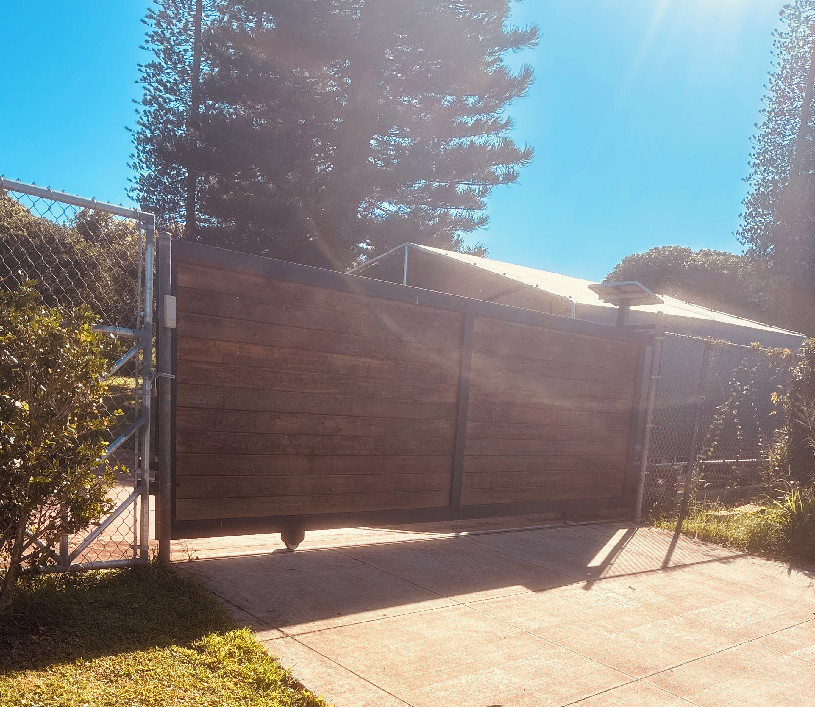 A gated area with a wooden fence, a metal gate, and a concrete pathway.
