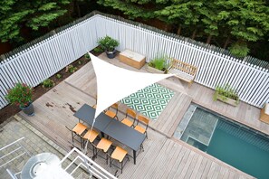 A deck with a pool, outdoor furniture, and a white fence. - Beach House in Deauville (Benerville-sur-Mer)