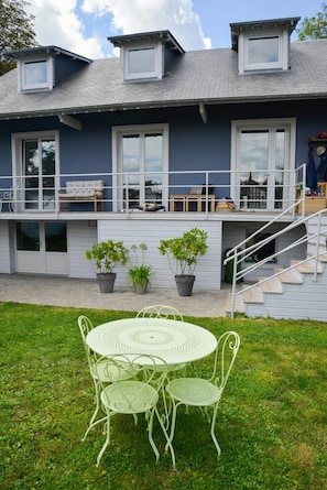 A two-story house with a balcony, a table with chairs, and potted plants. - Beach House in Deauville (Benerville-sur-Mer)