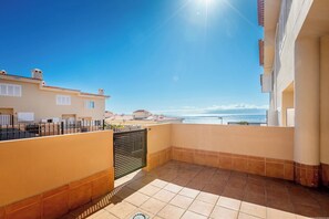 A balcony with a view of the sea, a tiled floor, and a building with a tiled roof. - Playa Negra 1 - Two Bed Townhouse (Puerto Santiago)