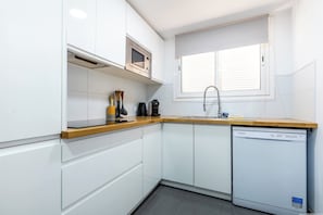 A compact kitchen with white cabinets, a microwave, a coffee maker, and a dishwasher. - Playa Negra 1 - Two Bed Townhouse (Puerto Santiago)