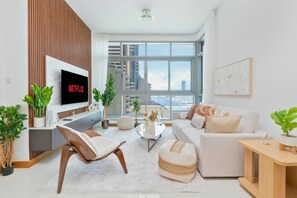 A modern living room with a flat-screen TV, a sofa, a chair, and a coffee table. - Warm 2BR Marina View at Iris Blue (Dubai)