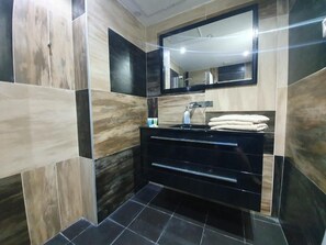 A modern bathroom with a black vanity, a mirror, and a towel rack. - HaRav Kuk Royal Suites (Jerusalem)