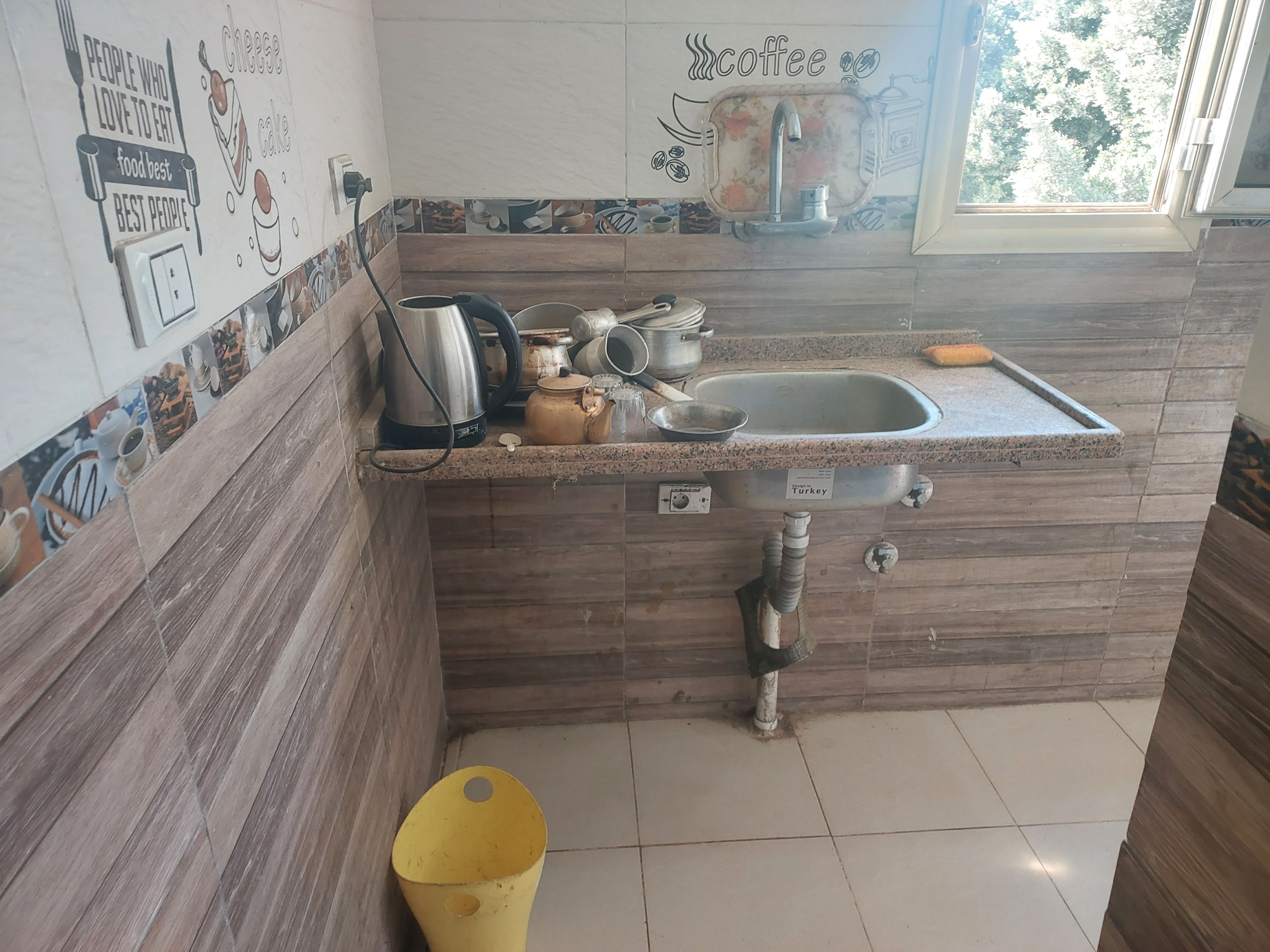 A kitchen with a sink, a kettle, and various pots and pans.