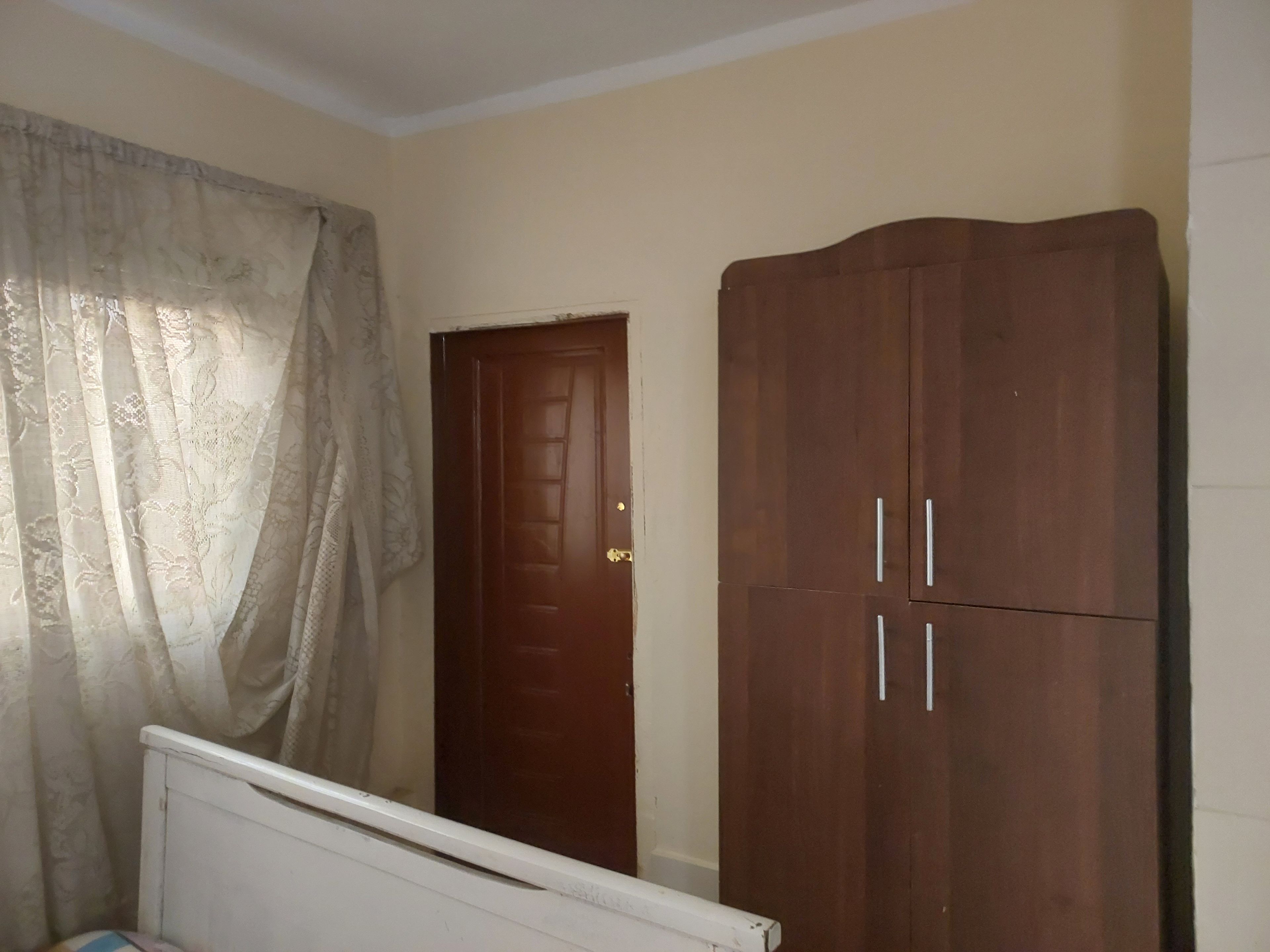 A bedroom with a bed, a wardrobe, and a door.