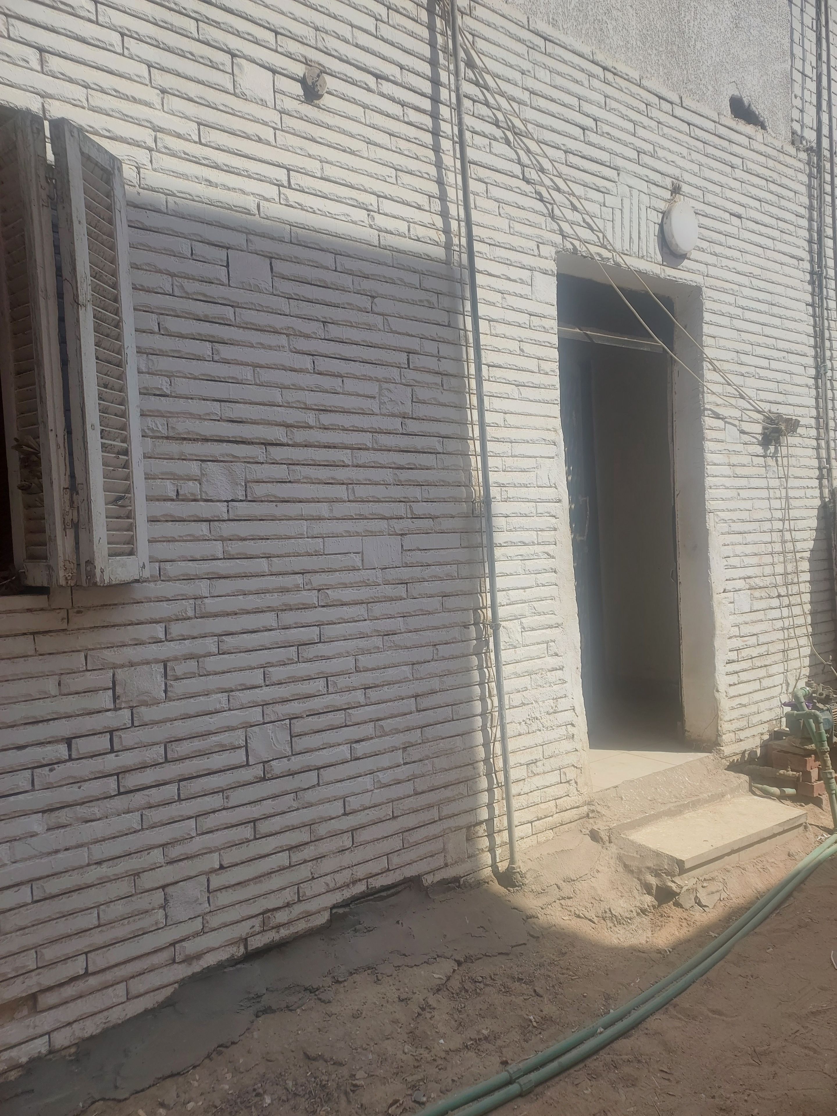 A brick building with a window and an open doorway.