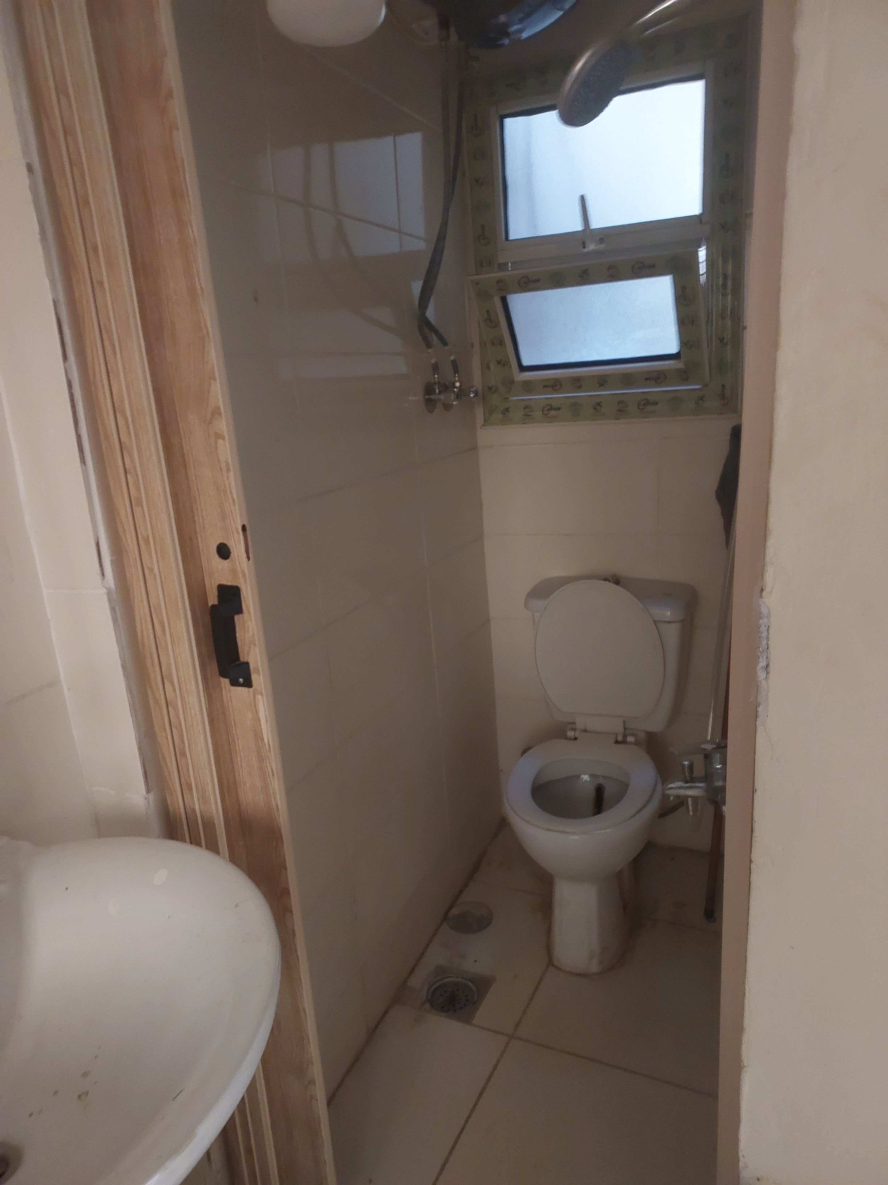 A small, narrow bathroom with a toilet, a window, and a sink.