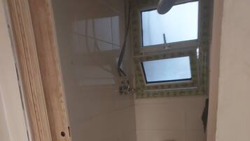 A small, narrow bathroom with a toilet, a window, and a sink.