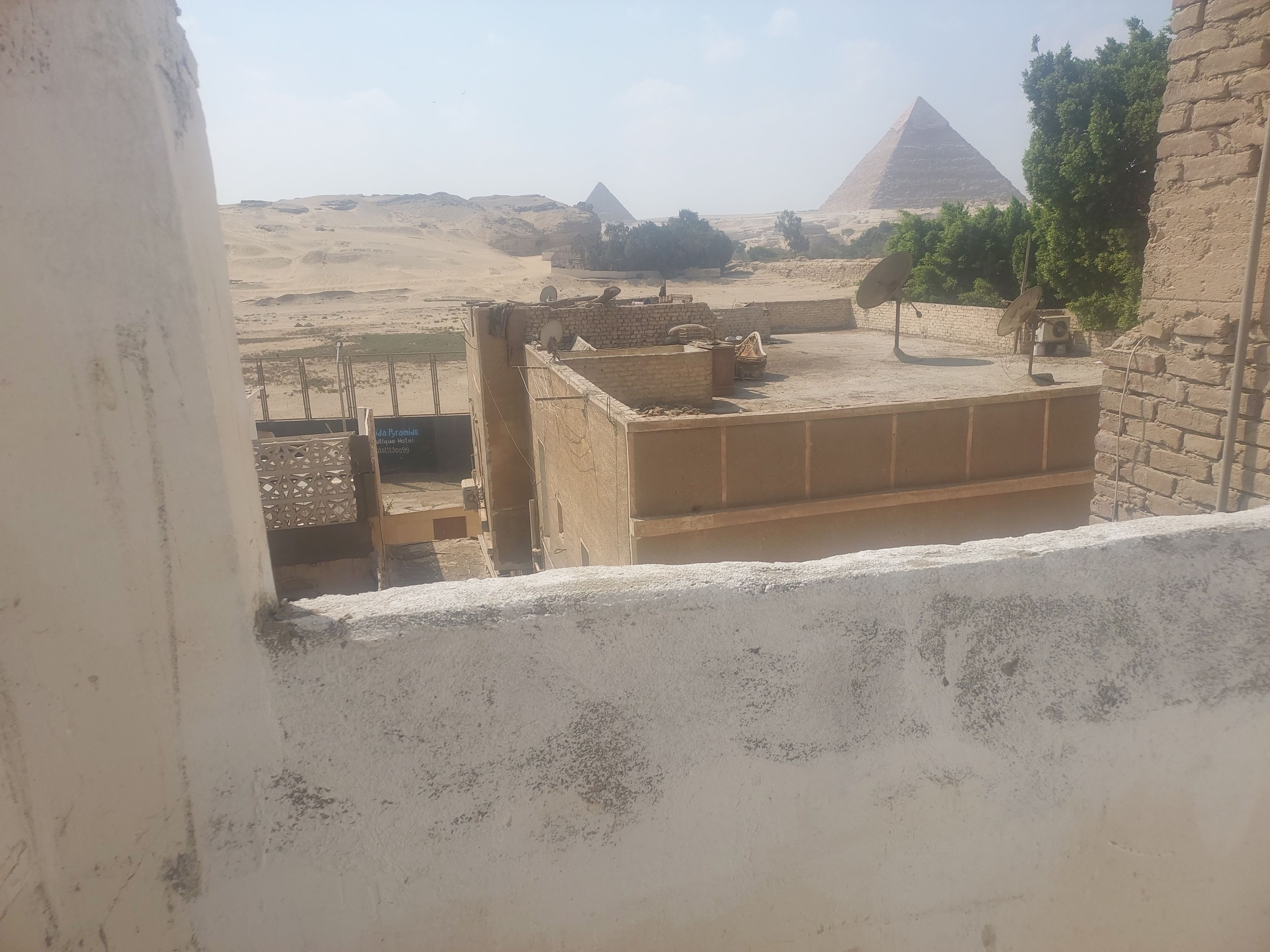 Vista de las Pirámides de Giza desde un balcón de hotel, con cielo despejado.