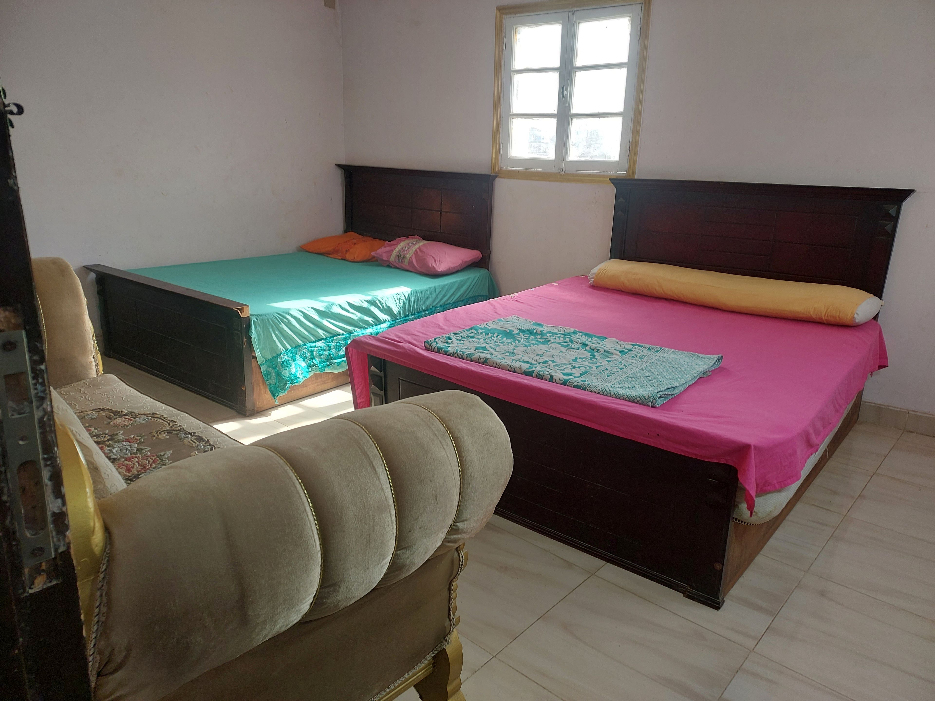 A room with two beds, a chair, and a window.