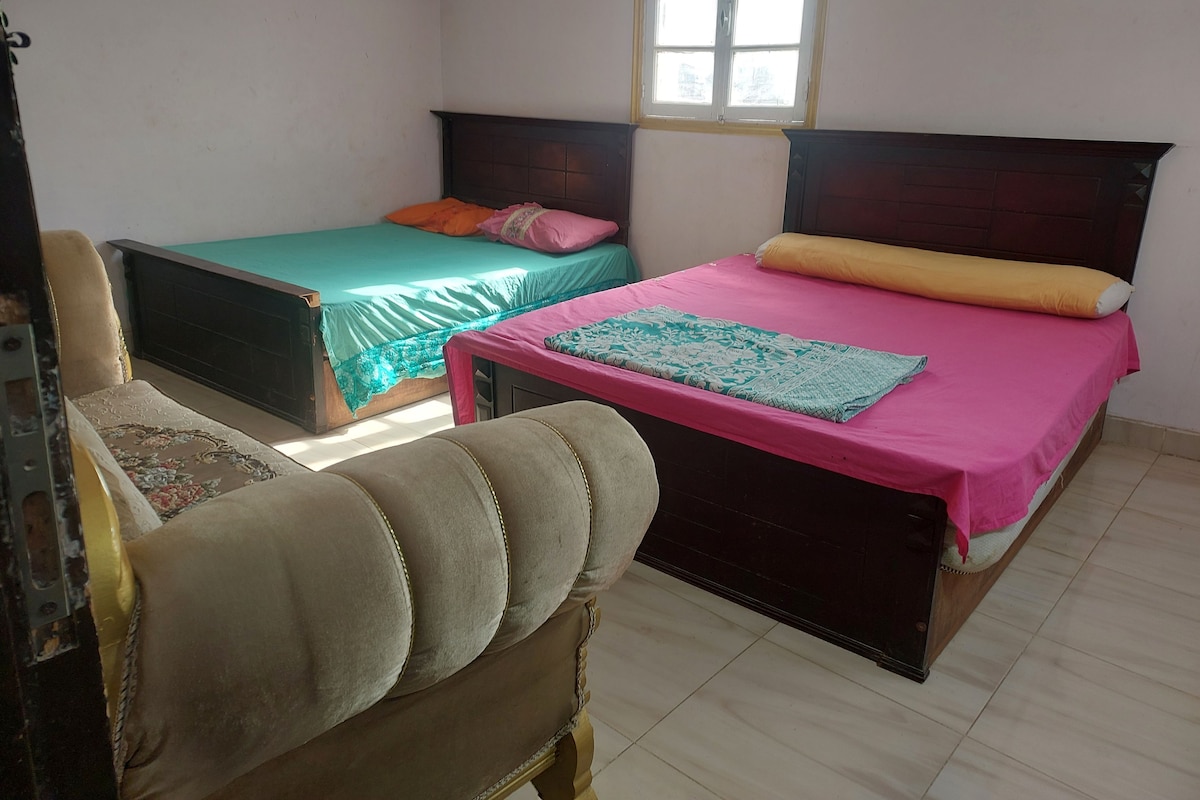 Una habitación con dos camas, una silla y una ventana.