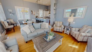 Un salon moderne avec un canapé gris, des fauteuils à rayures et une table basse agrémentée d’objets décoratifs.