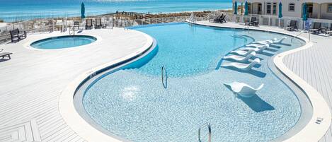 Una piscina con muelle de madera, una silla de salvavidas y vista al océano.