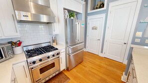 A modern kitchen with stainless steel appliances, white cabinetry, and a wooden floor. - Punta Vista Mare 4 Bedroom Home (Destin)