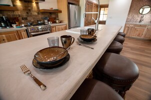 Una cocina con una encimera larga, electrodomésticos modernos y un comedor con mesa para dos.