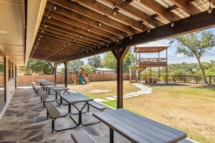 Un espacio al aire libre con mesas de picnic y un parque infantil al fondo.