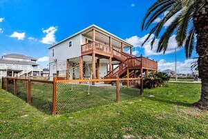 A two-story house with a wooden deck and stairs leading to a balcony.