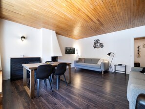 A modern living room with a dining area, wooden ceiling, and a sofa. - Bright central apartment - 4 guests (Val-d'Isère)
