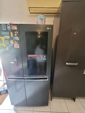 Ein schwarzer LG-Kühlschrank mit digitaler Anzeige, Wasserspender und verschiedenen Magneten.