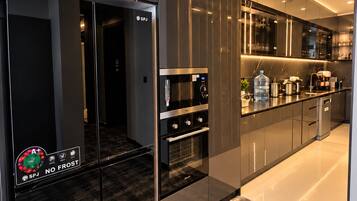 A modern kitchen with a built-in oven, microwave, and a refrigerator with a digital display.