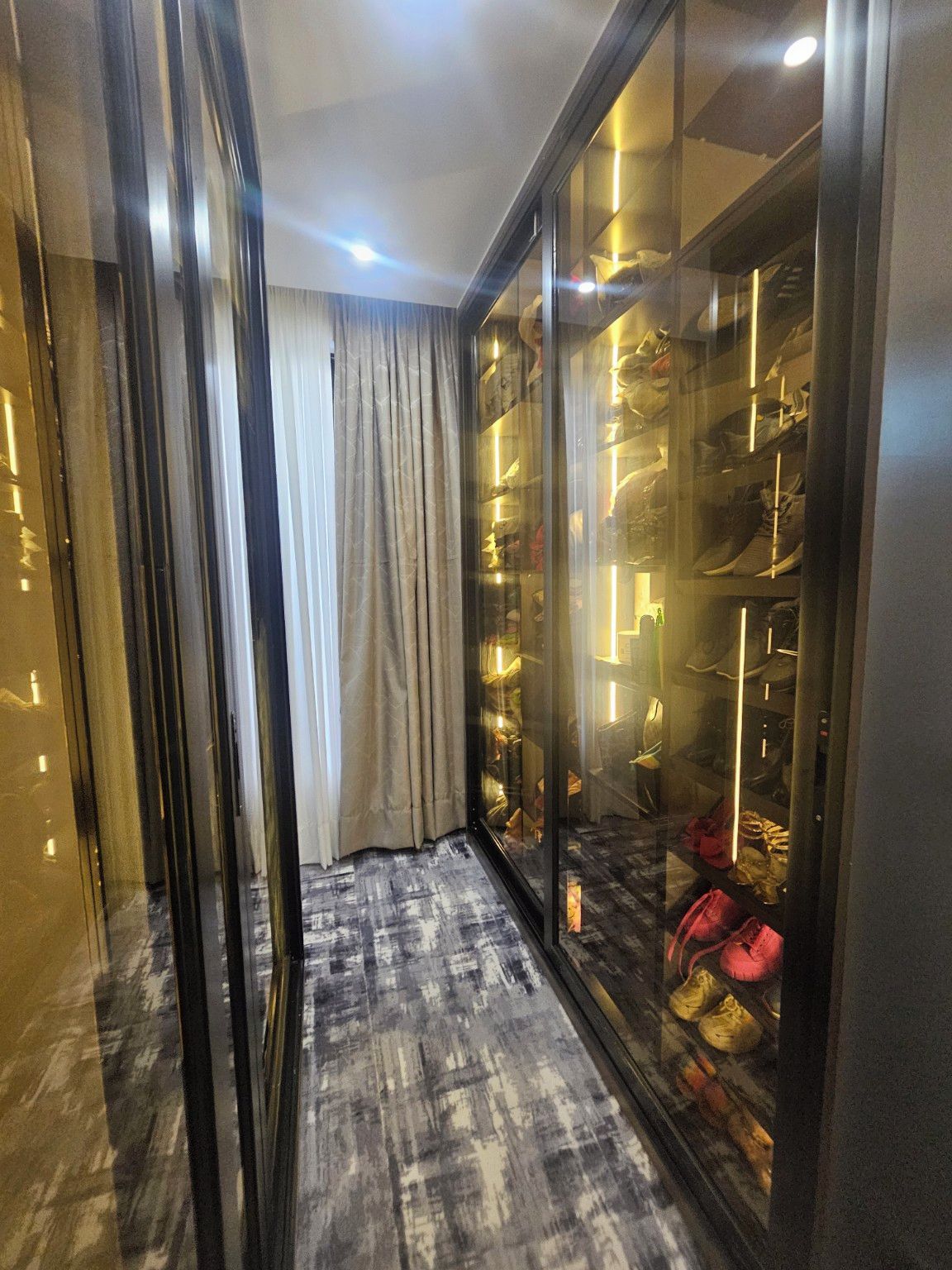 A walk-in closet with a mirrored wardrobe and a patterned floor.