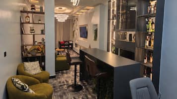 Um interior moderno com área de bar, assentos e uma estante.