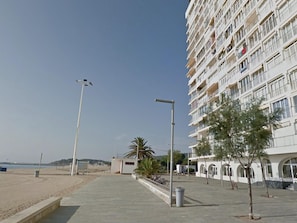 A beachfront hotel with a multi-story structure, a paved walkway, and a beach in the background. - Charming studio, spectacular sea view - 4 guests (Platja d'Aro)