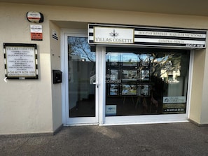 A storefront with a glass door, signs for holiday rentals, and contact information. - Charming studio, spectacular sea view - 4 guests (Platja d'Aro)
