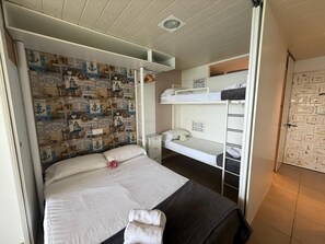 A room with a bunk bed, a single bed, and a wall with nautical-themed wallpaper. - Charming studio, spectacular sea view - 4 guests (Platja d'Aro)