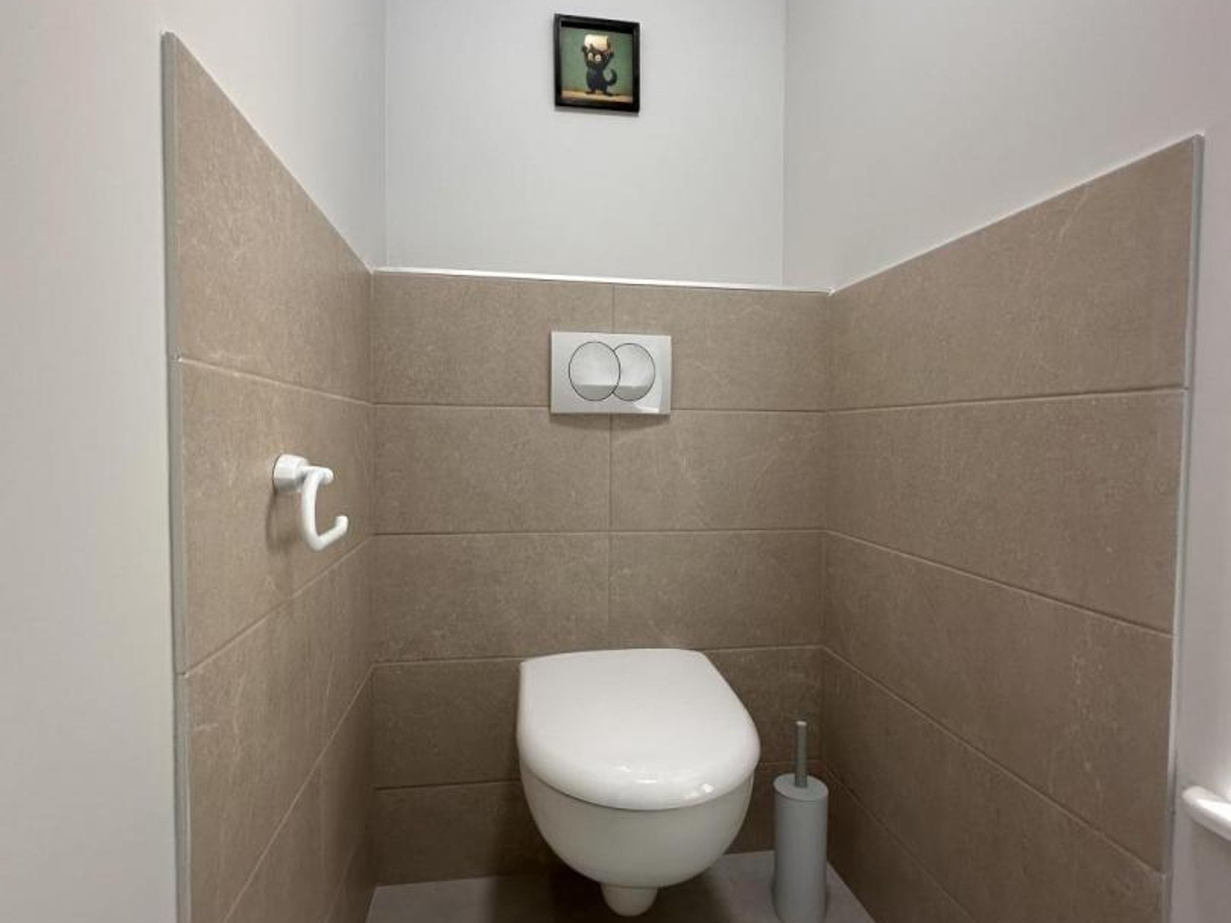 A small, modern bathroom with a toilet, a hand dryer, and a wall-mounted toilet paper holder.