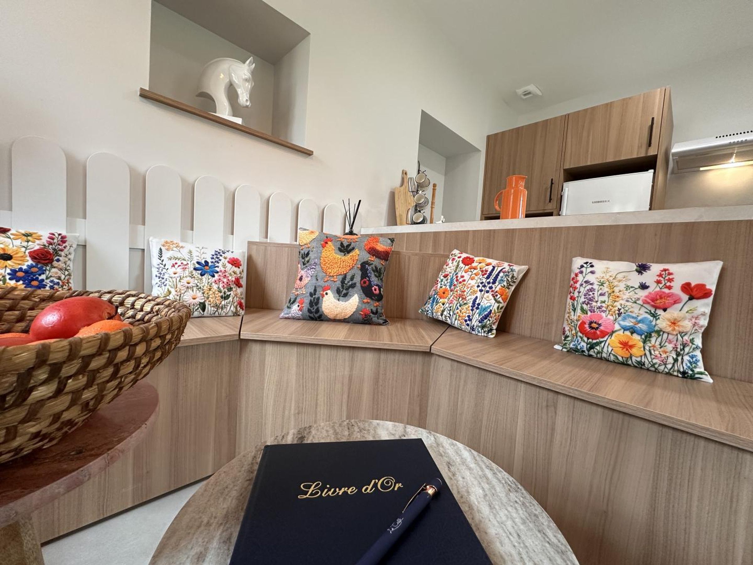 Eine moderne Küche mit integriertem Sitzplatz, einem Obstkorb und dekorativen Kissen.