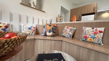 A modern kitchen with a built-in bench, a basket of fruit, and decorative pillows.