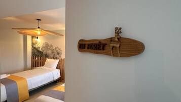 Un dormitorio con una cama, una mesita de noche, un adorno de madera en la pared y un ventilador de techo.