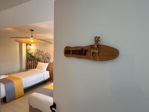 Un dormitorio con una cama, una mesita de noche, un adorno de madera en la pared y un ventilador de techo.
