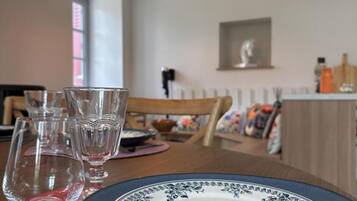 A dining table with a plate and glasses, a chair, and a window in the background.