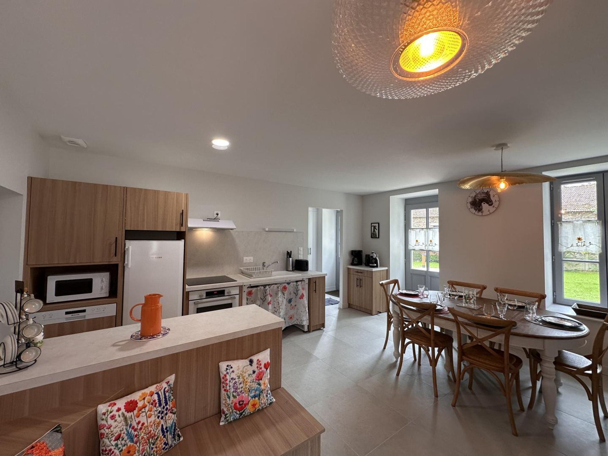 A modern kitchen with a central island, wooden cabinets, and a dining area with a round table and chairs.