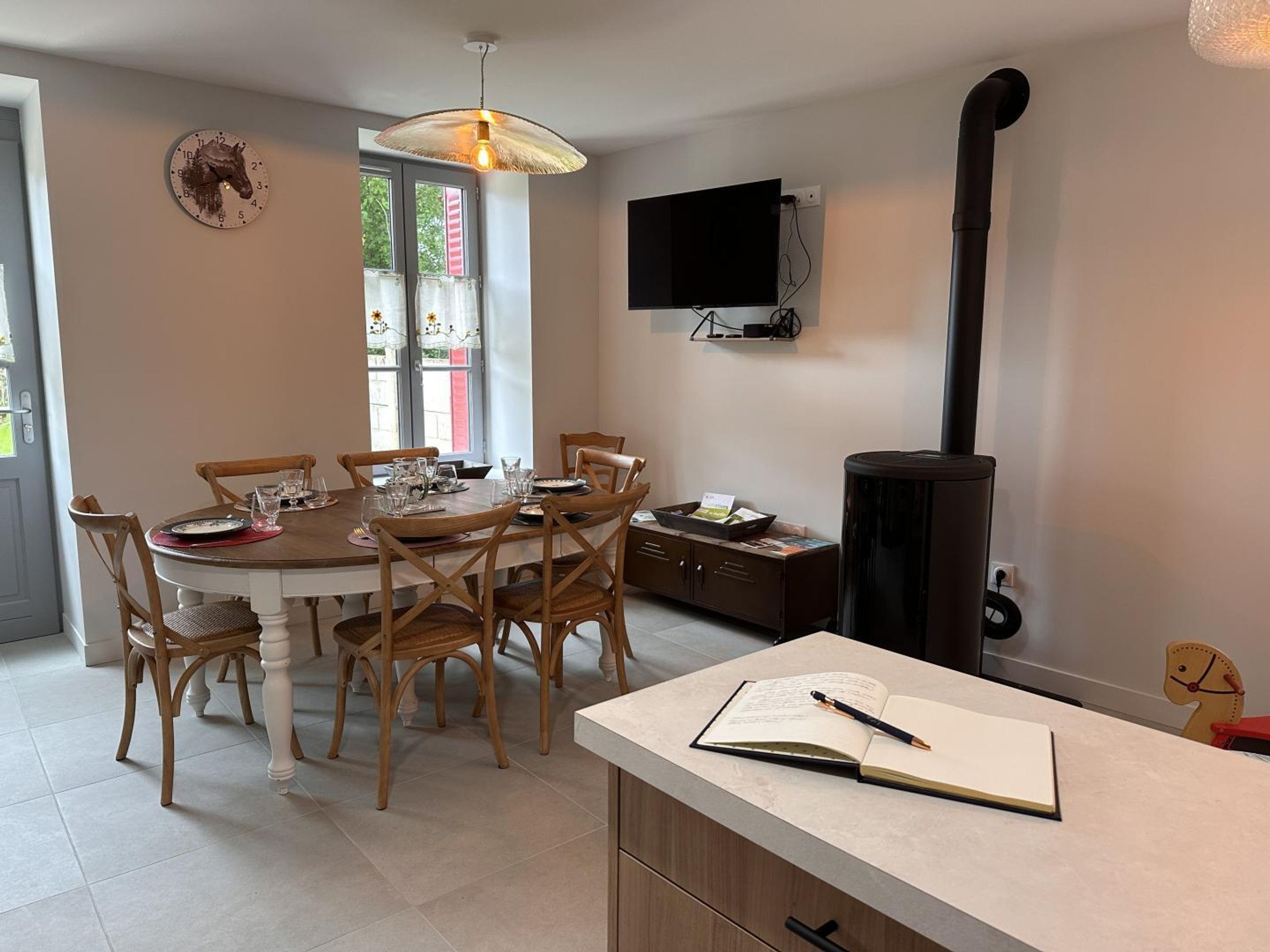 Un coin repas comprenant une table ronde, des chaises, un téléviseur fixé au mur et une cheminée.