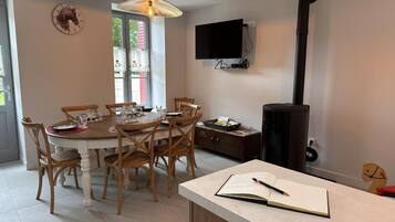 Un coin repas comprenant une table ronde, des chaises, un téléviseur fixé au mur et une cheminée.