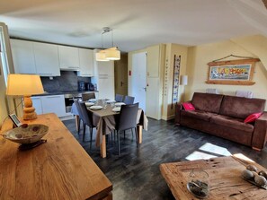 A compact living space with a dining area, a sofa, and a kitchen. - Cozy apartment with mountain views - 6 guests (Saint-Gervais-les-Bains)