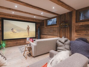 A cozy living room with a large flat-screen TV, wooden walls, and a comfortable sofa. - Chalet with pool, pets welcome, Mont Blanc view - 11 guests (Les Houches)